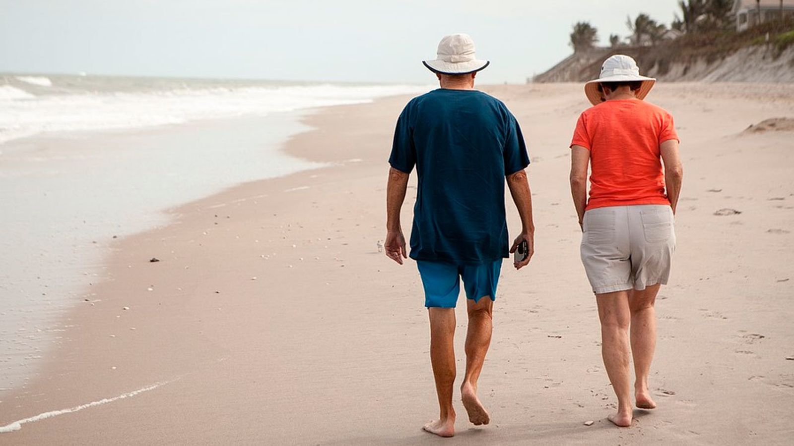 Una pareja de jubilados pasean por la playa
