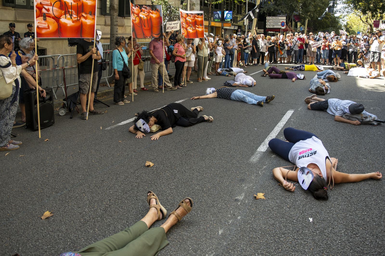 Varias personas se tumban en el suelo como si fueran algunas de las víctimas de los atentados durante una concentración convocada por la plataforma 17A frente a la Delegación de Gobierno, a 17 de agosto de 2023
