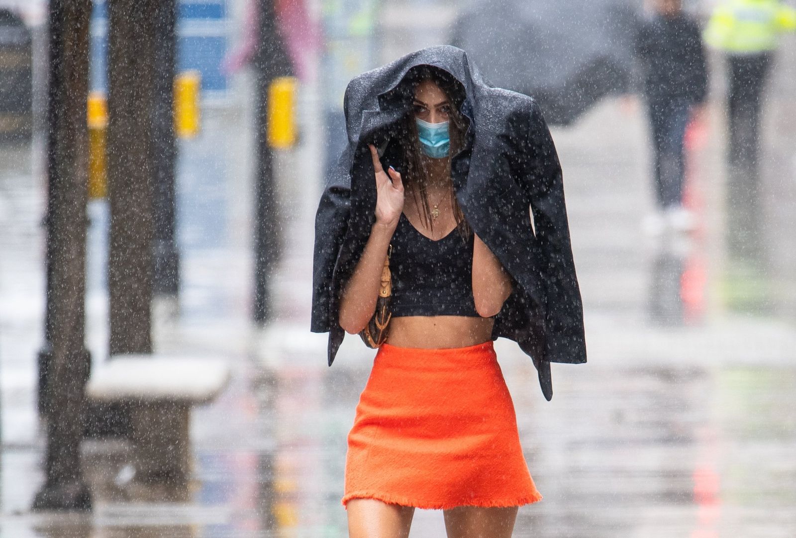 Una mujer se resguarda de la lluvia bajo una chaqueta