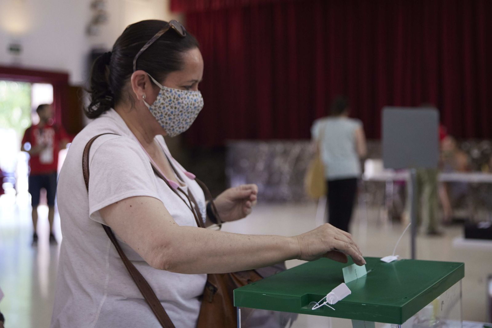 Una mujer deposita su voto en una mesa electoral andaluza