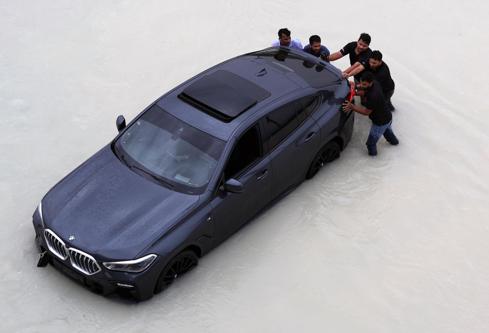 Varias personas empujan un coche averiado a causa de las lluvias en Dubai