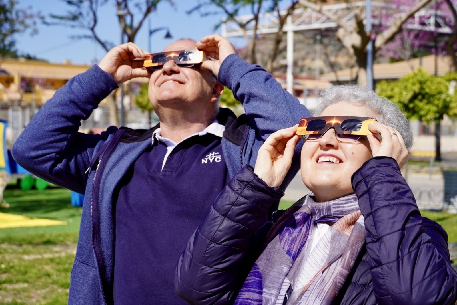 Dos personas observan un eclipse solar con gafas protectoras