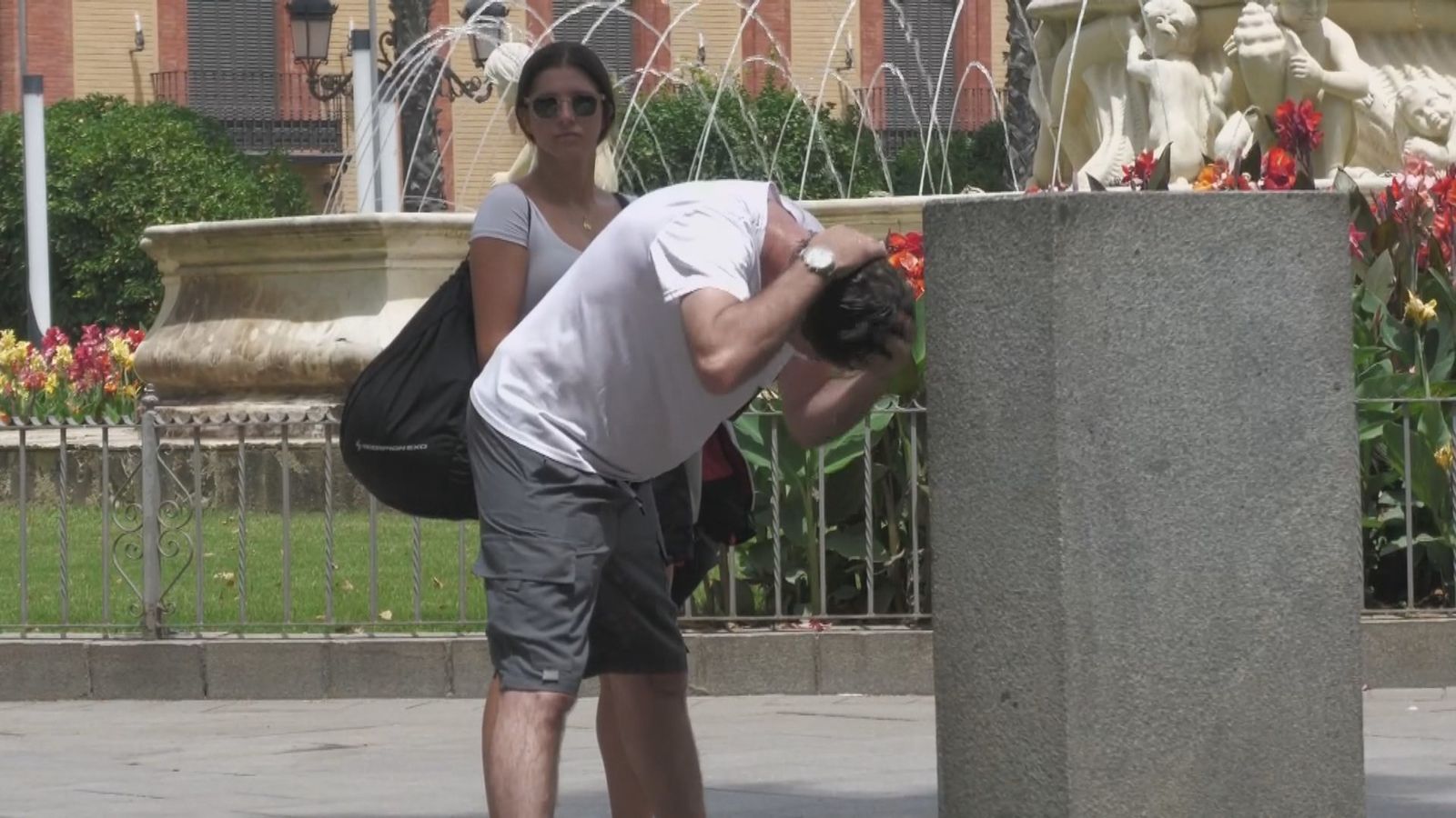 Un hombre se refresca en una fuente