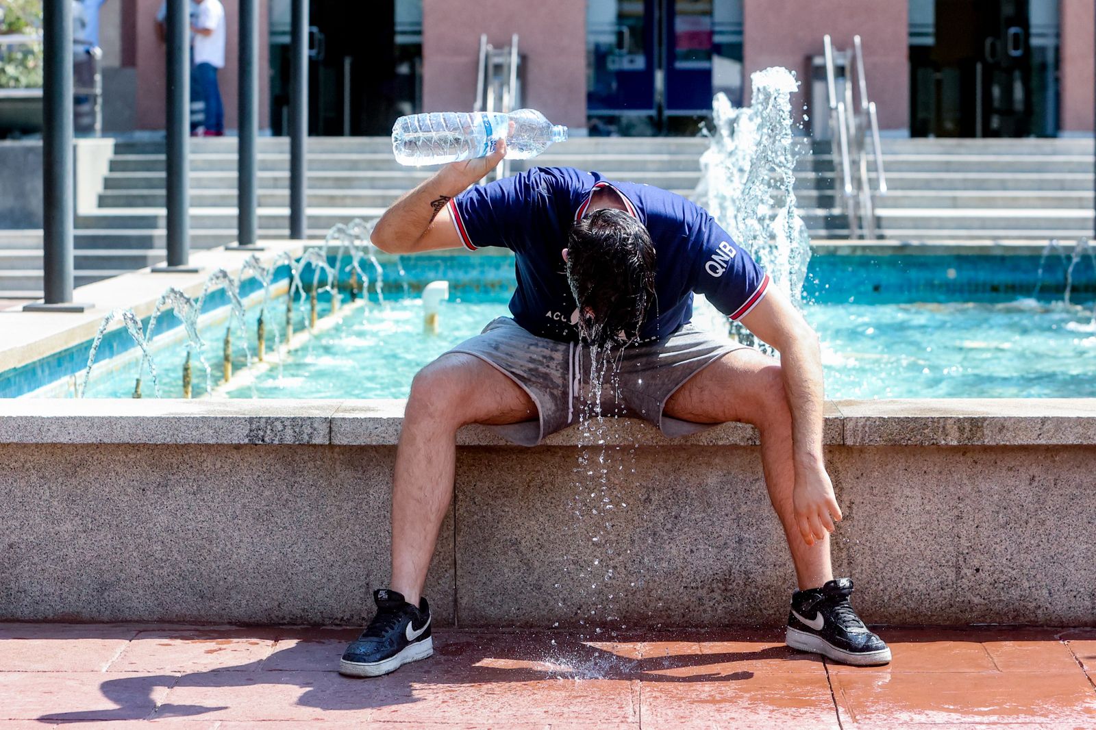 Un joven se tira una botella de agua por encima para combatir el calor