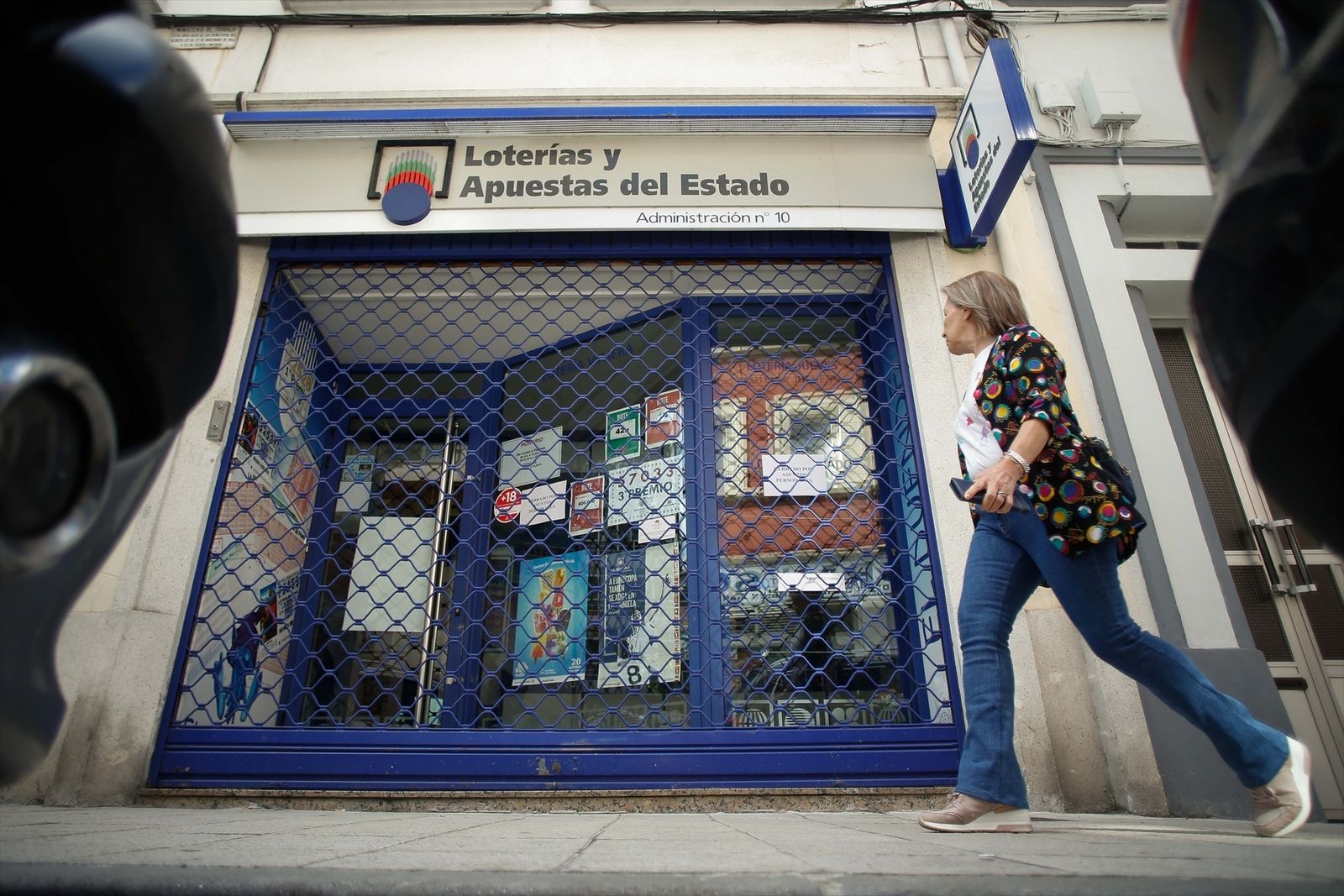 Una mujer pasa frente a una administración de Lotería cerrada