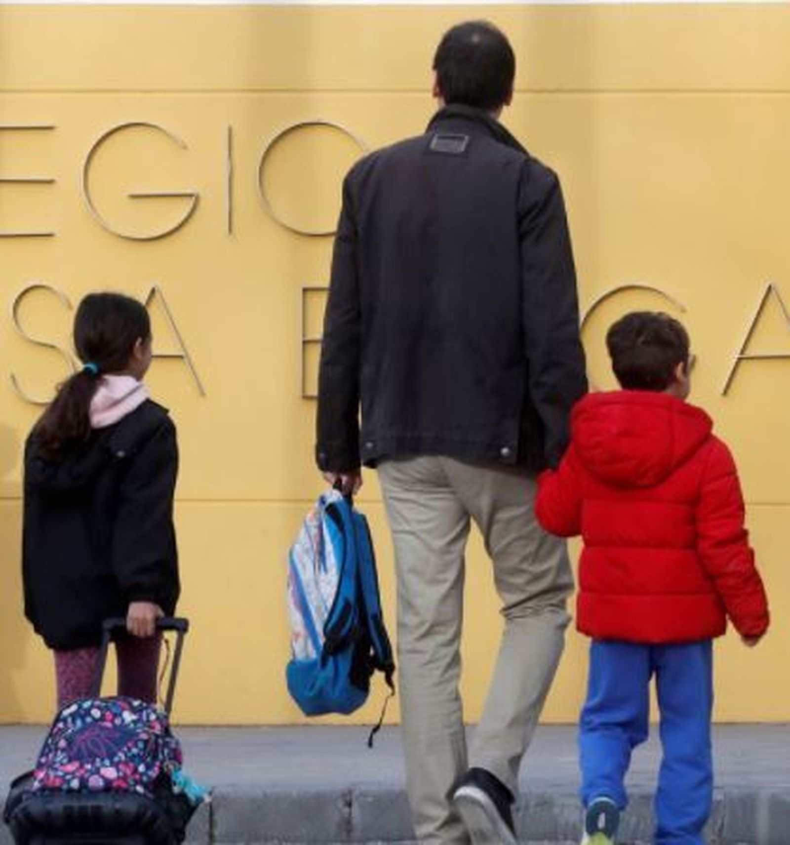 Un padre acompaña a sus hijos al colegio