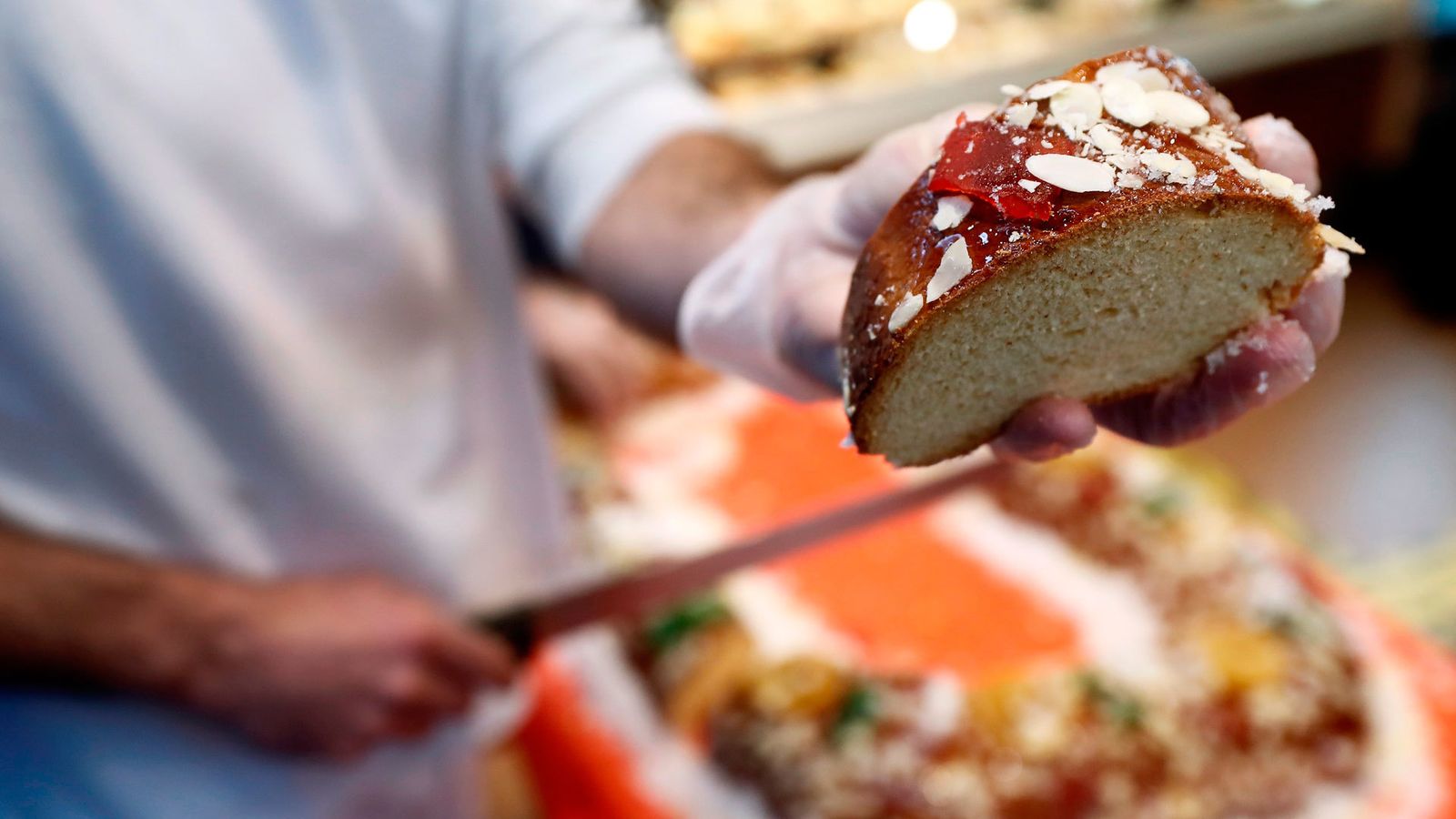 Un pastelero corta un trozo de roscón, el típico dulce de la fiesta de Reyes