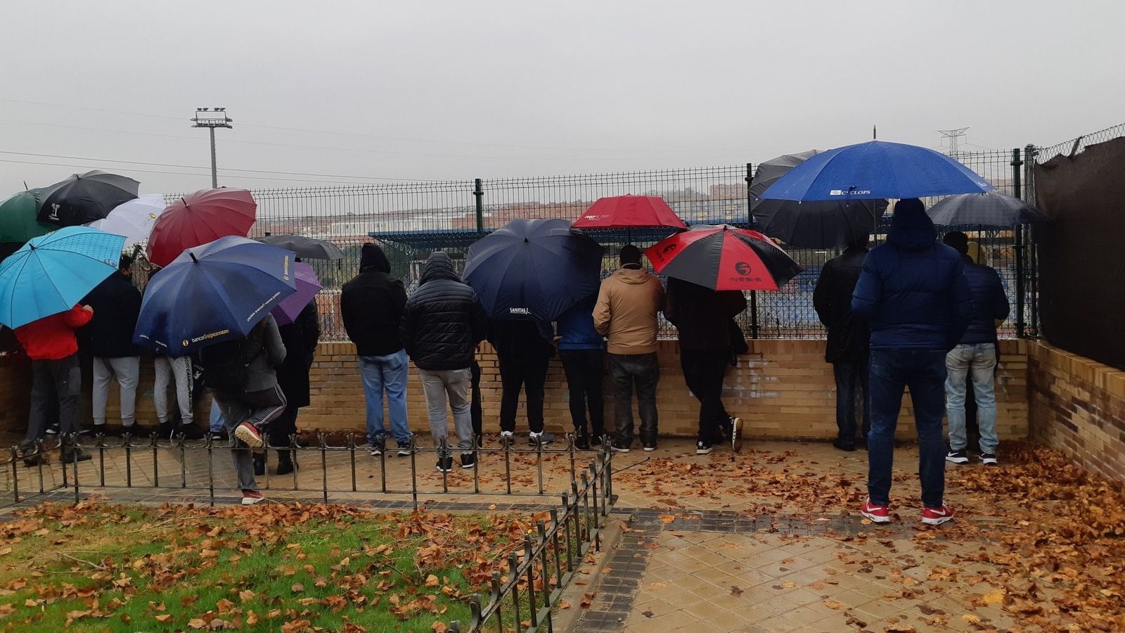 Padres tras una valla para ver jugar al fútbol a sus hijos