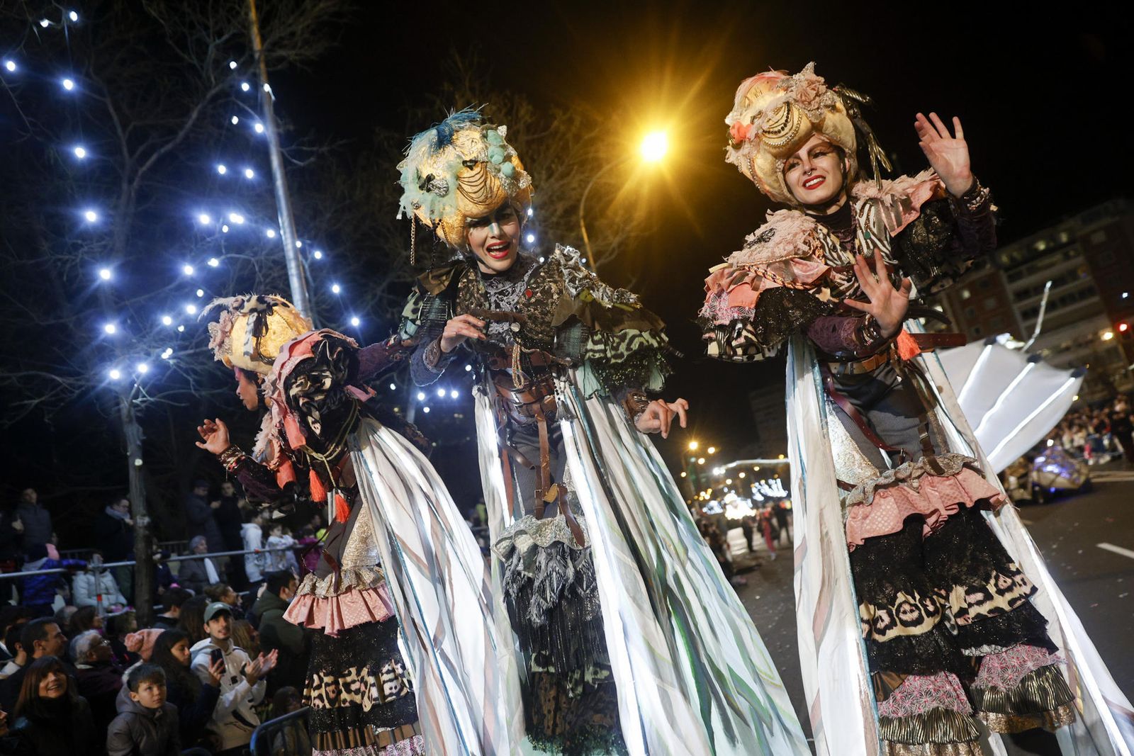 Tres mujeres sobre zancos, y ataviadas con vestiduras de fantasía desfilan y amenizan la cabalgata de Reyes que se celebra este jueves en Madrid