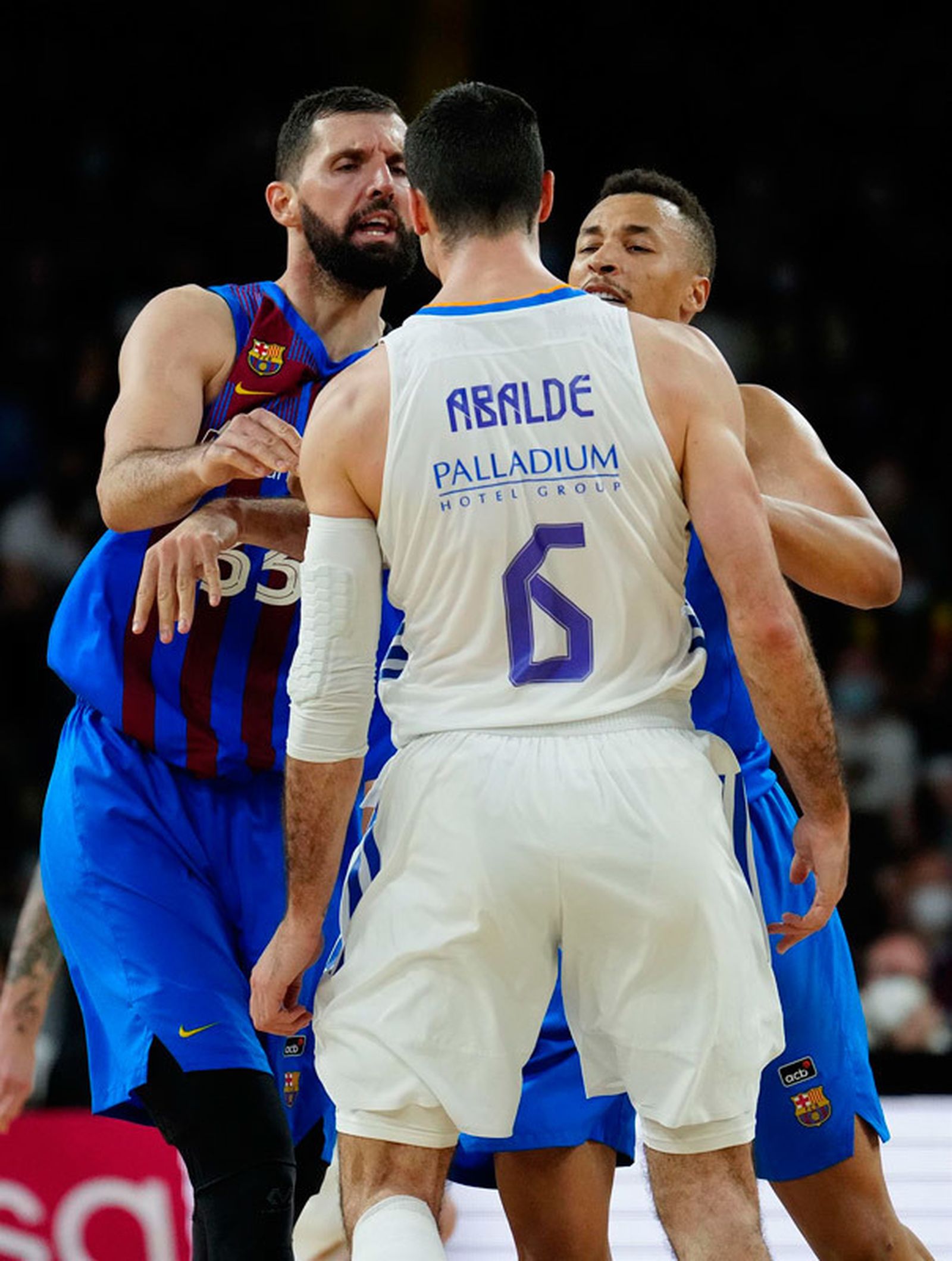 El ala-pívot del Barcelona Nikola Mirotic (i) se encara con Alberto Abalde (c), alero del Real Madrid, durante el partido de la Liga Endesa que disputan Barcelona y Real Madrid este domingo en el pabellón Palau Blaugrana