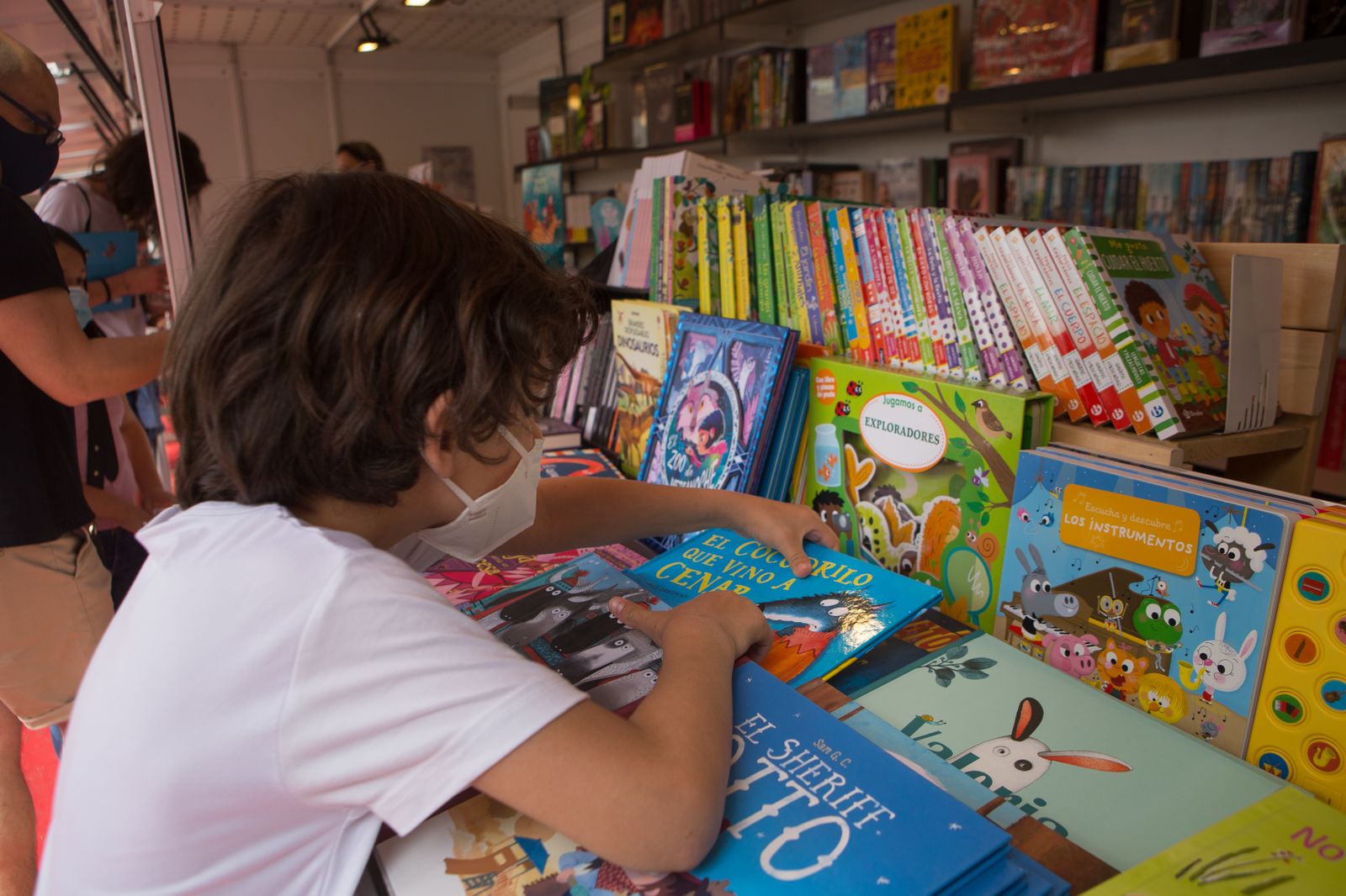 Un niño busca un cuento en un estand de libros