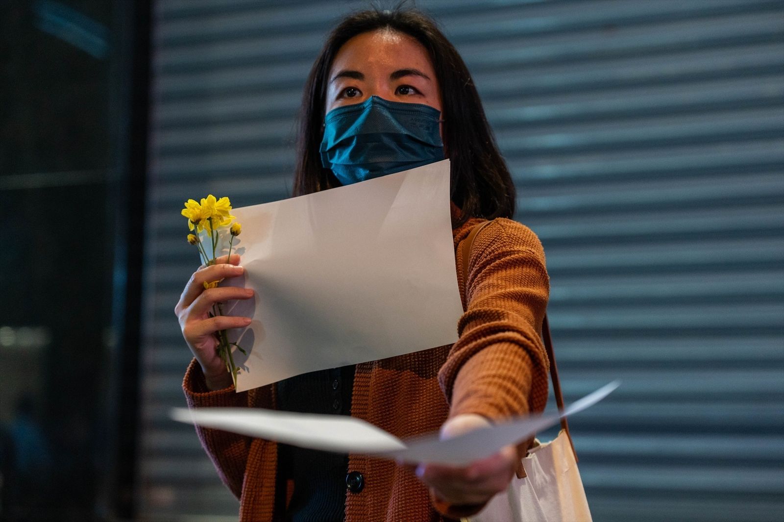 Un manifestante reparte hojas de papel en blanco durante una protesta de solidaridad con los que se manifiestan en China contra las políticas de cero COVID del gobierno.