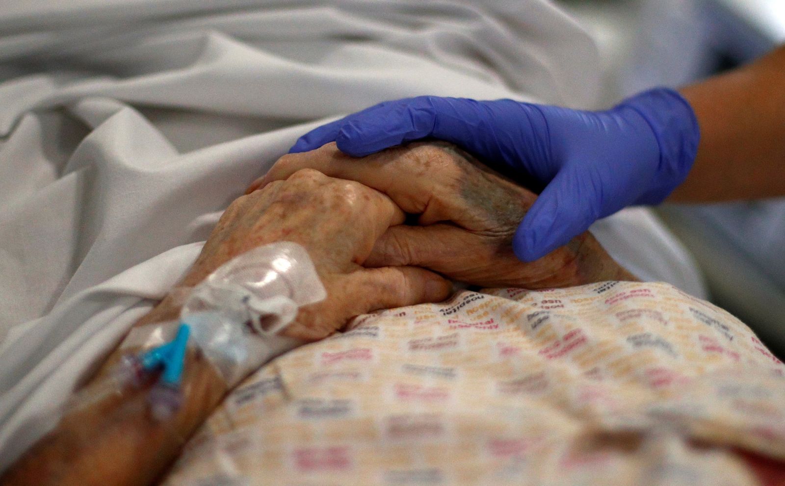 Detalle de la mano de un médico sobre la de un paciente anciano