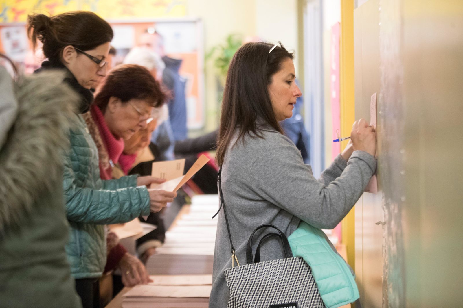 Una ciudadana rellena su papeleta apoyada en la pared de su colegio electoral