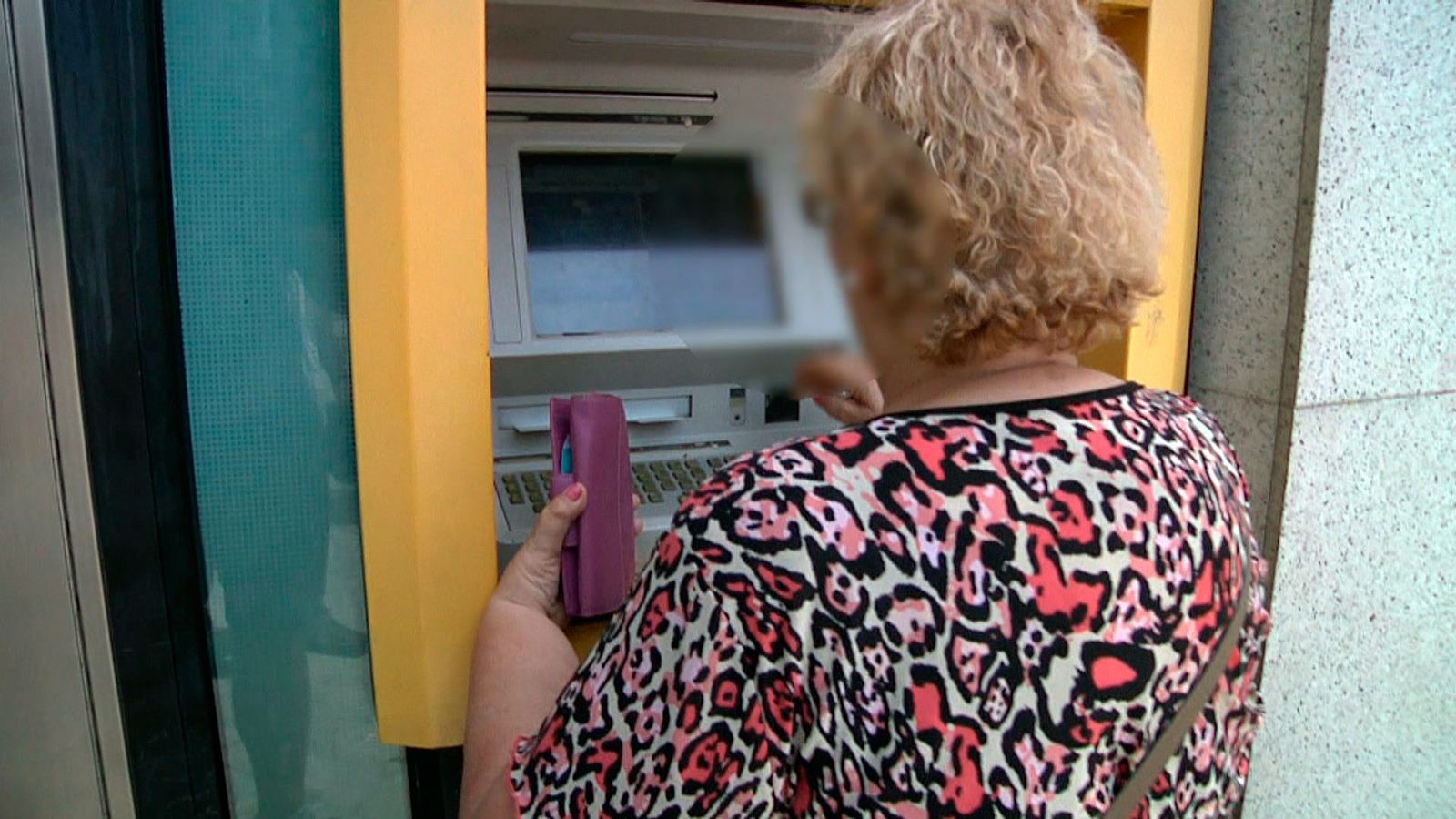 Una mujer mayor saca dinero de un cajero automático