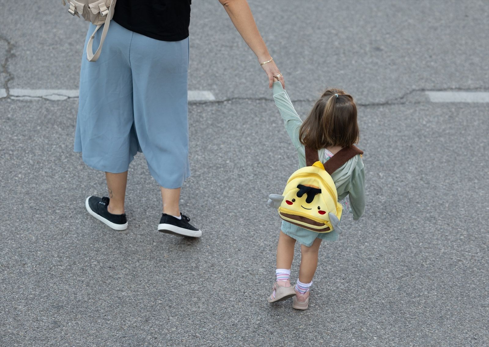 Una niña de infantil se dirige con su madre al colegio