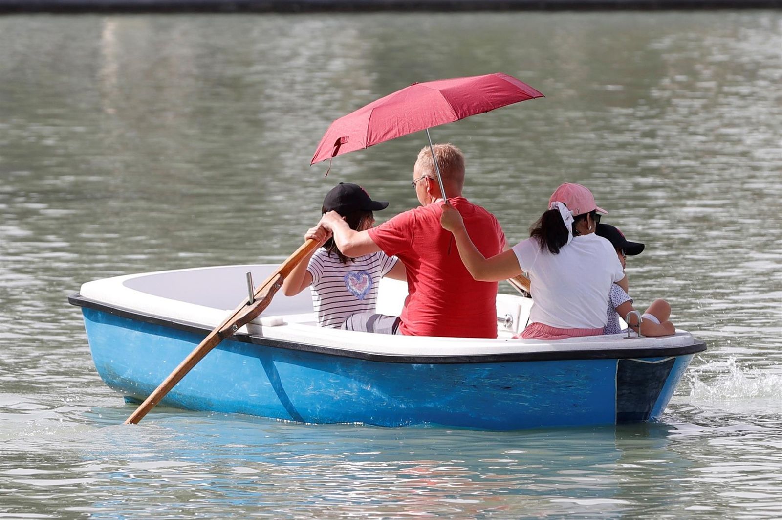 Lo cierto es que los turistas vienen a Madrid muy bien preparados. Aquí vemos a una familia que sabe protegerse mientras disfruta de un paseo en barca en el lago del Retiro.