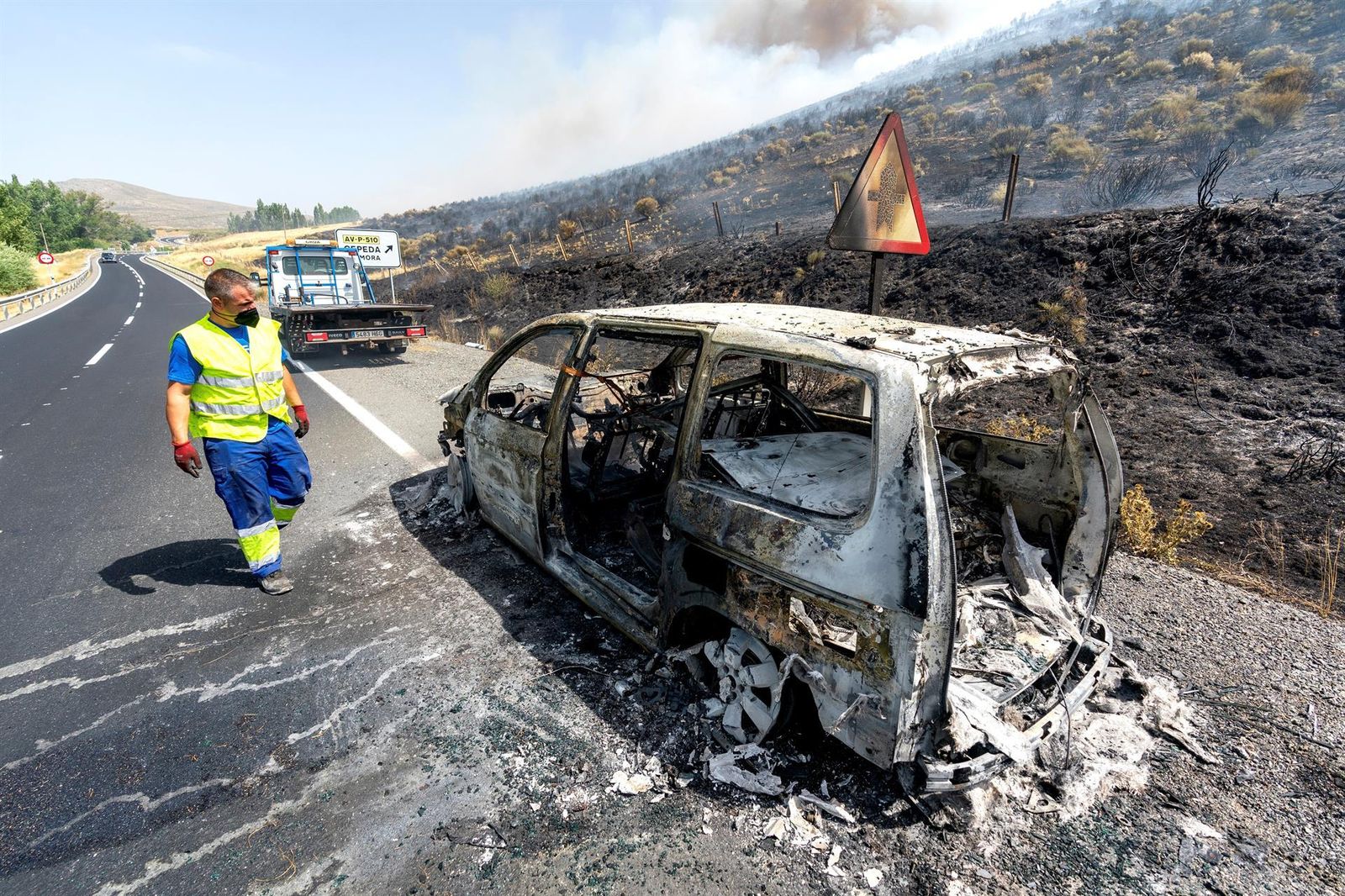 Vista del vehículo incendiando que ha generado un fuego a la altura del kilómetro 39 de la N-502 de Ávila este sábado