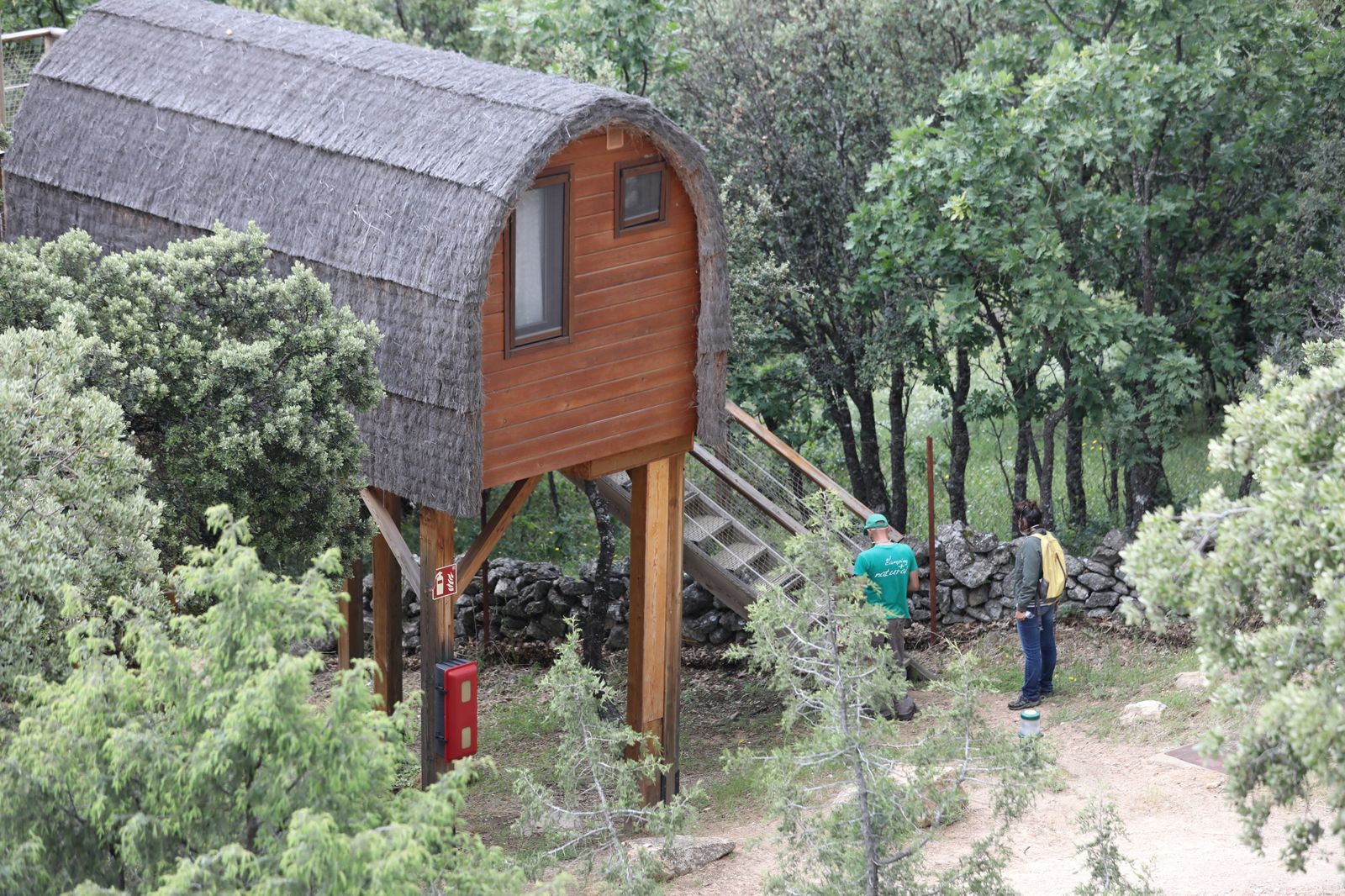 Un trabajador del camping le enseña a una clienta una Cabaña en el árbol del Camping Monte Holiday en Gargantilla del Lozoya