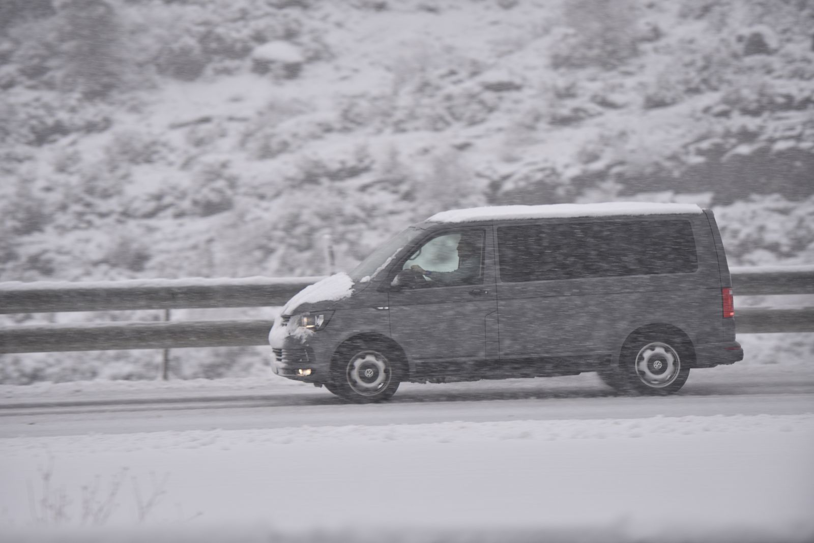 Un coche circula por una carretera nevada