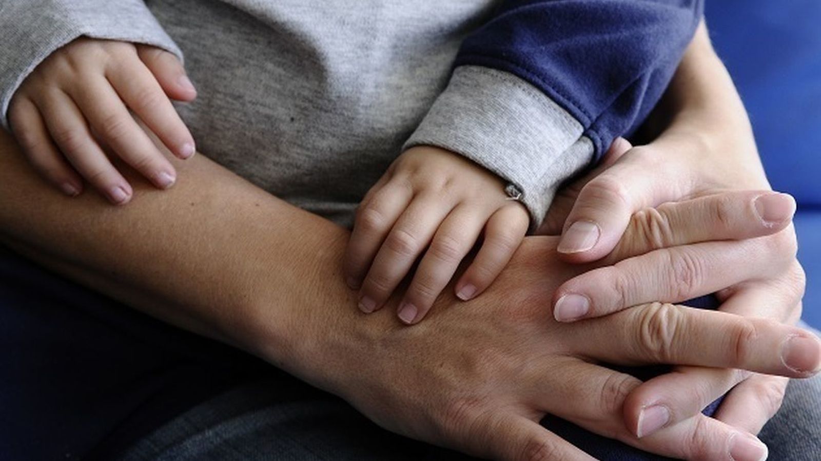 Una mujer sostiene en su regazo a un menor