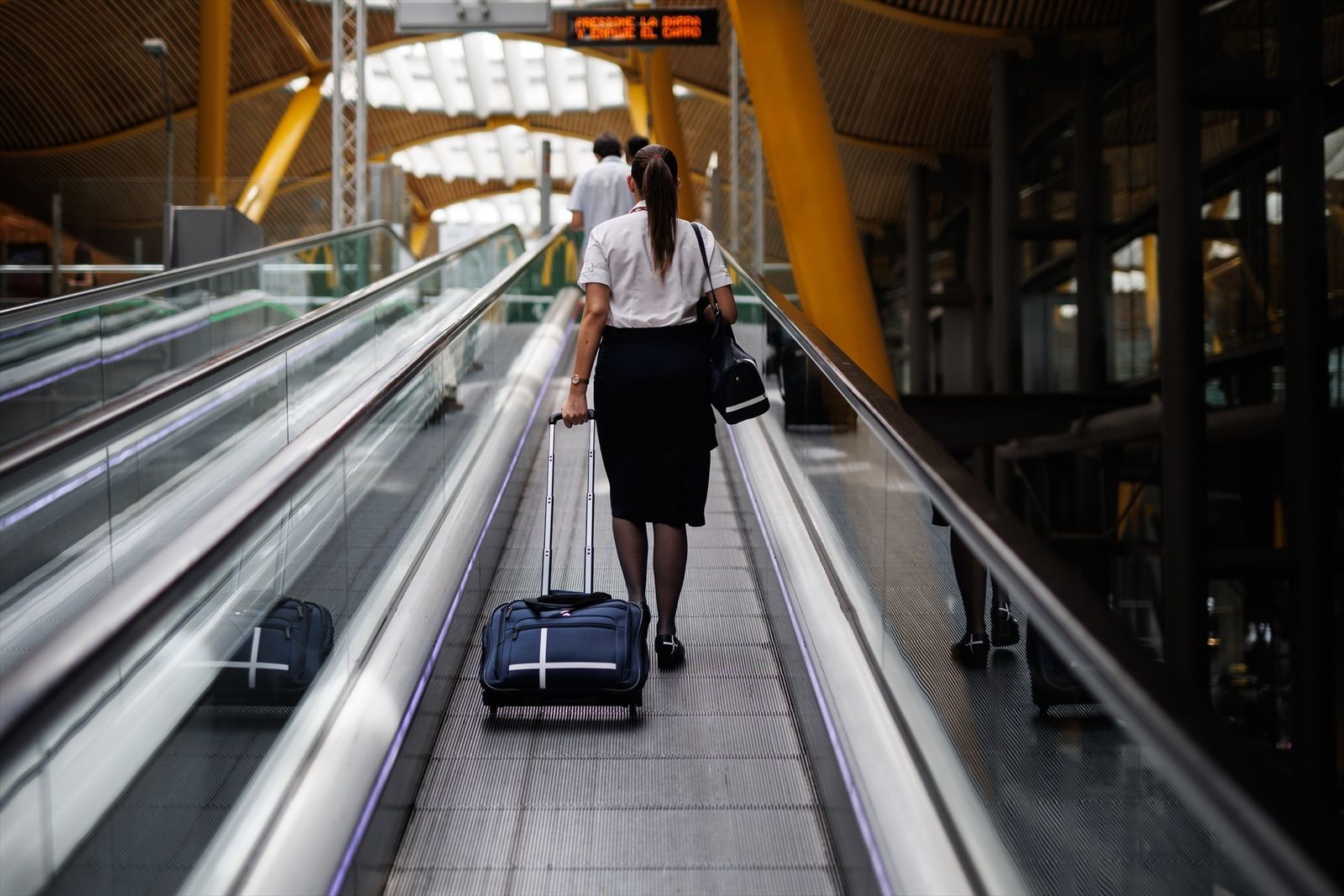 Una azafata en las escaleras mecánicas de la Terminal 4 del aeropuerto de Barajas