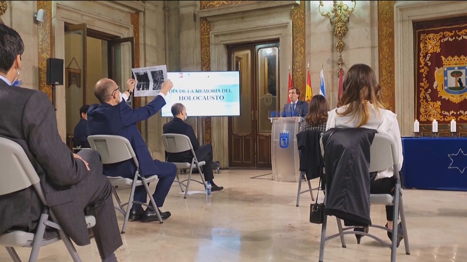 Un edil del PSOE muestra a Almeida una foto de Largo Caballero en un acto sobre las víctimas del Holocausto