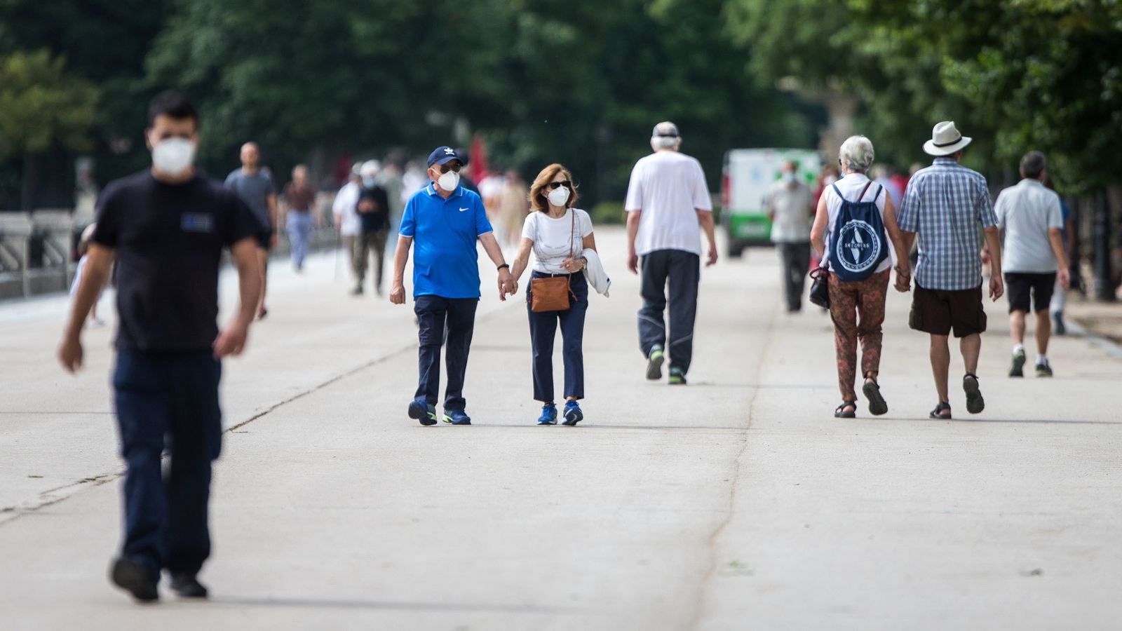 Varias personas pasean protegidas con mascarillas después de la reapertura del Parque de El Retiro