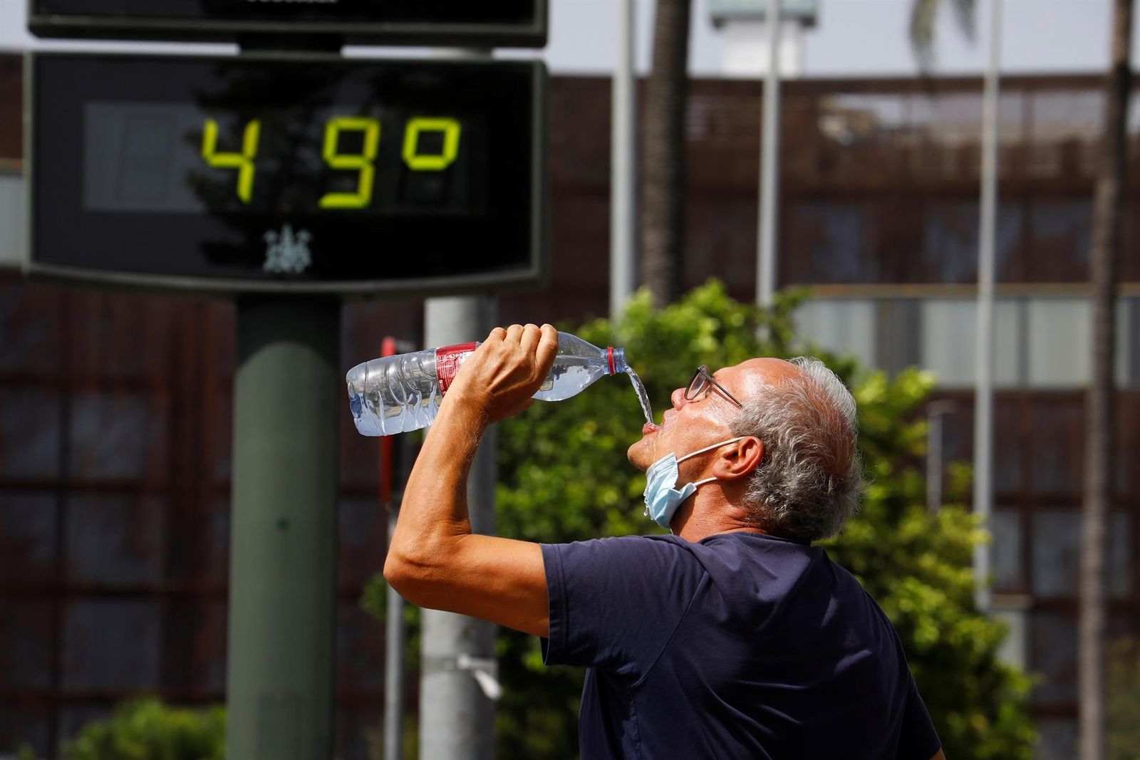 Con el termómetro al sol 'recalentado', un turista se hidrata en pleno centro de Córdoba. El termómetro en realidad podría marcar 45 o 46 grados.