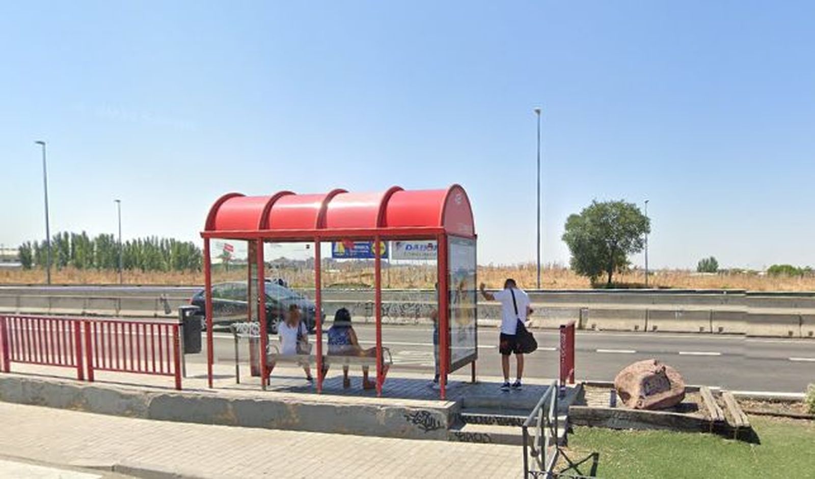 Vecinos de Parque Miraflores (Fuenlabrada) esperan el autobús junto a la carretera que les separa de Móstoles