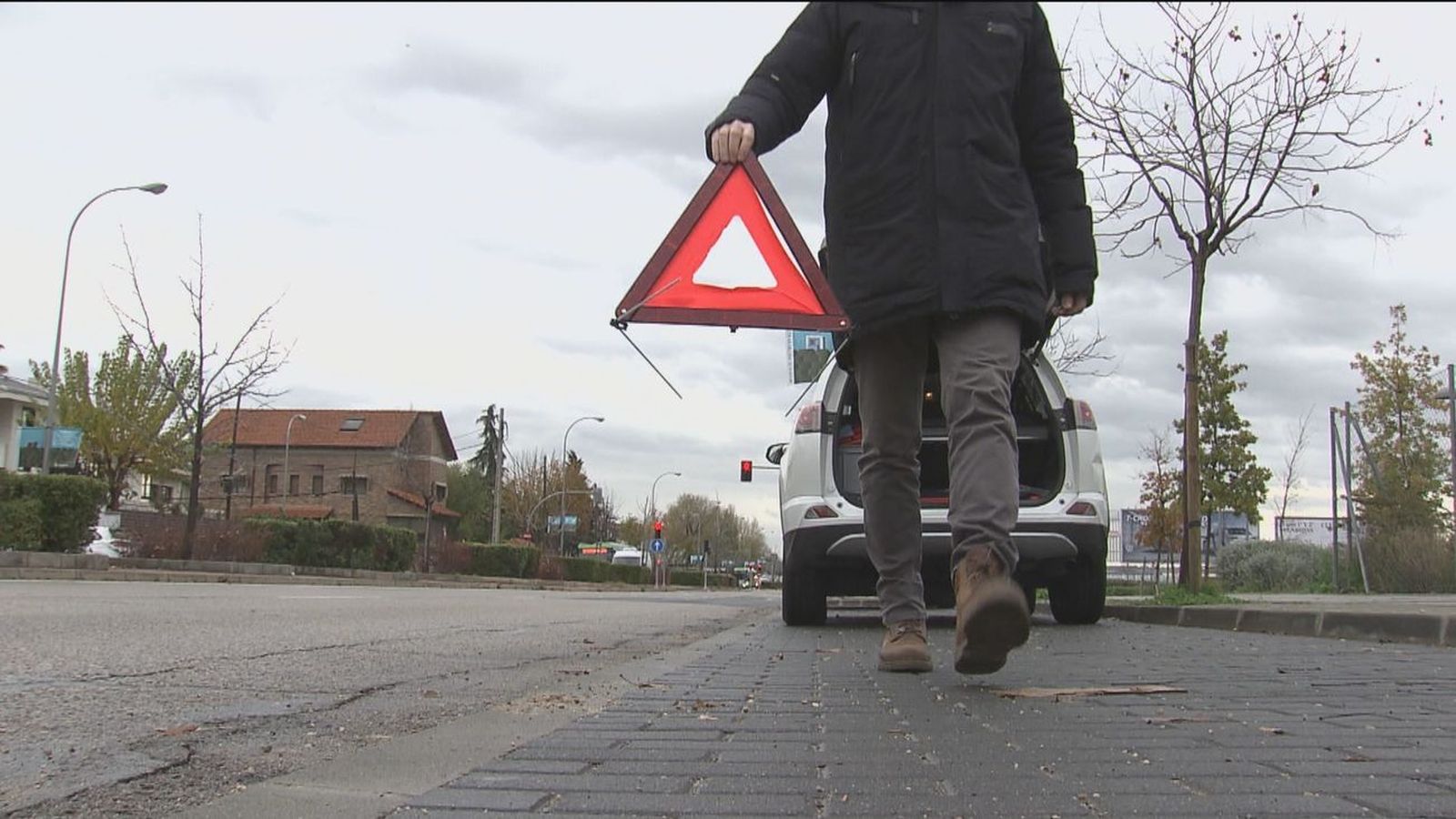 Una persona se dispone a señalizar su vehículo con un triángulo reflectante