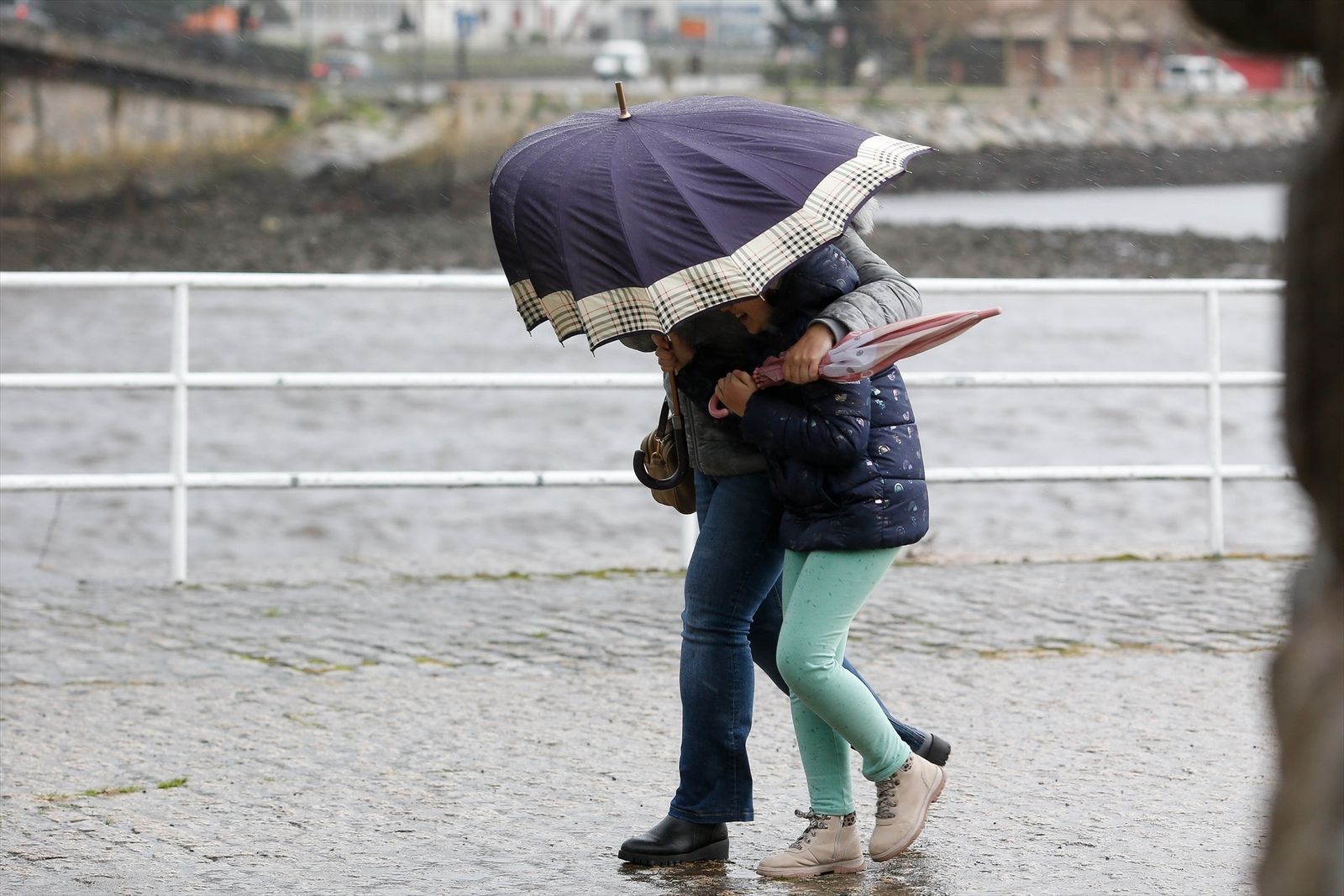 Dos personas se resguardan de la lluvia bajo un paraguas