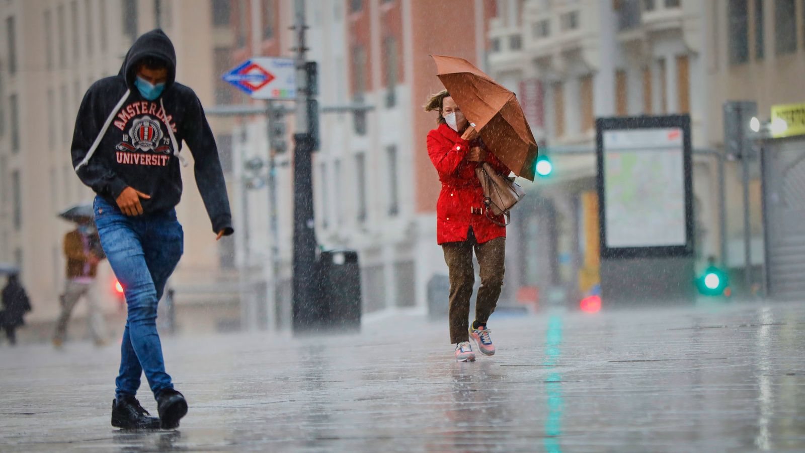 Transeúntes caminan por el centro de Madrid con lluvias y viento