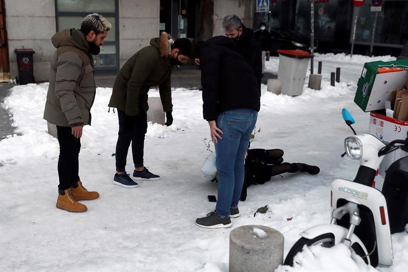 Madrileños atienden a una persona en el suelo tras caer por el hielo