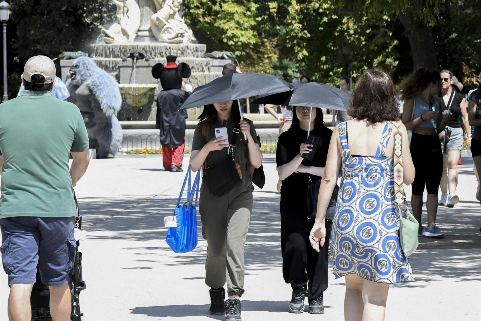 Unos turistas se protegen del calor en El Retiro
