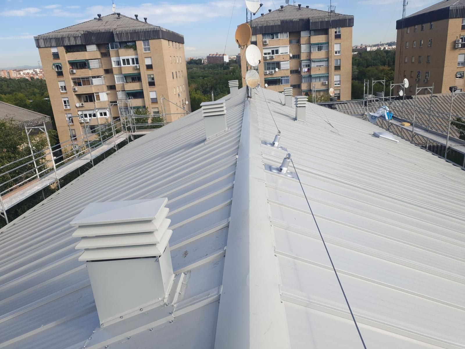 En primer plano el nuevo tejado de un inmueble. Al fondo, edificios con uralita