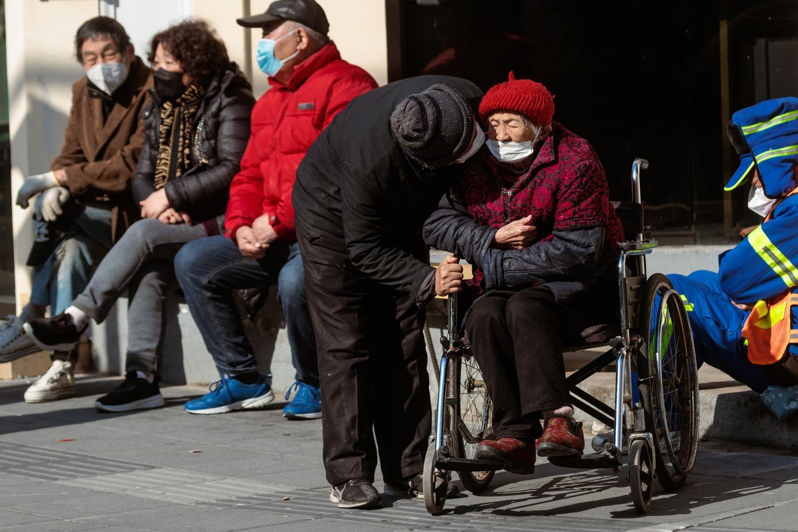 Personas mayores sentadas para disfrutar del sol en la calle, en Shanghai, China
