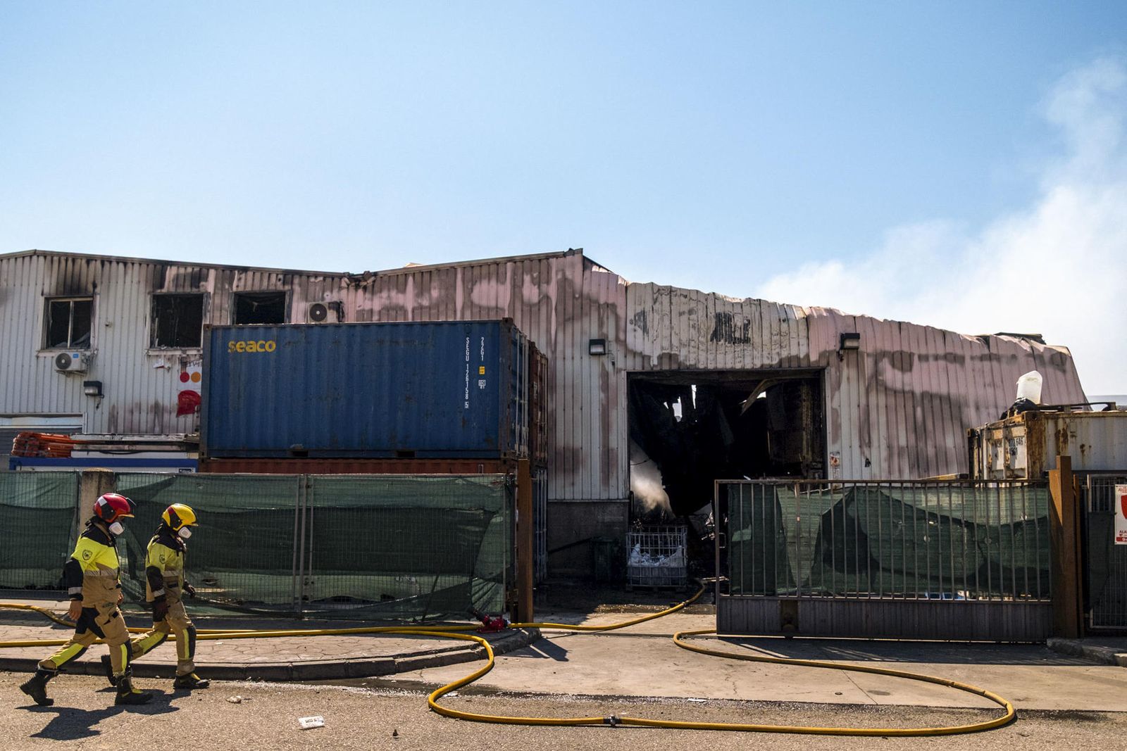 Bomberos caminan junto a la nave siniestrada en Azuqueca de Henares (Guadalajara)