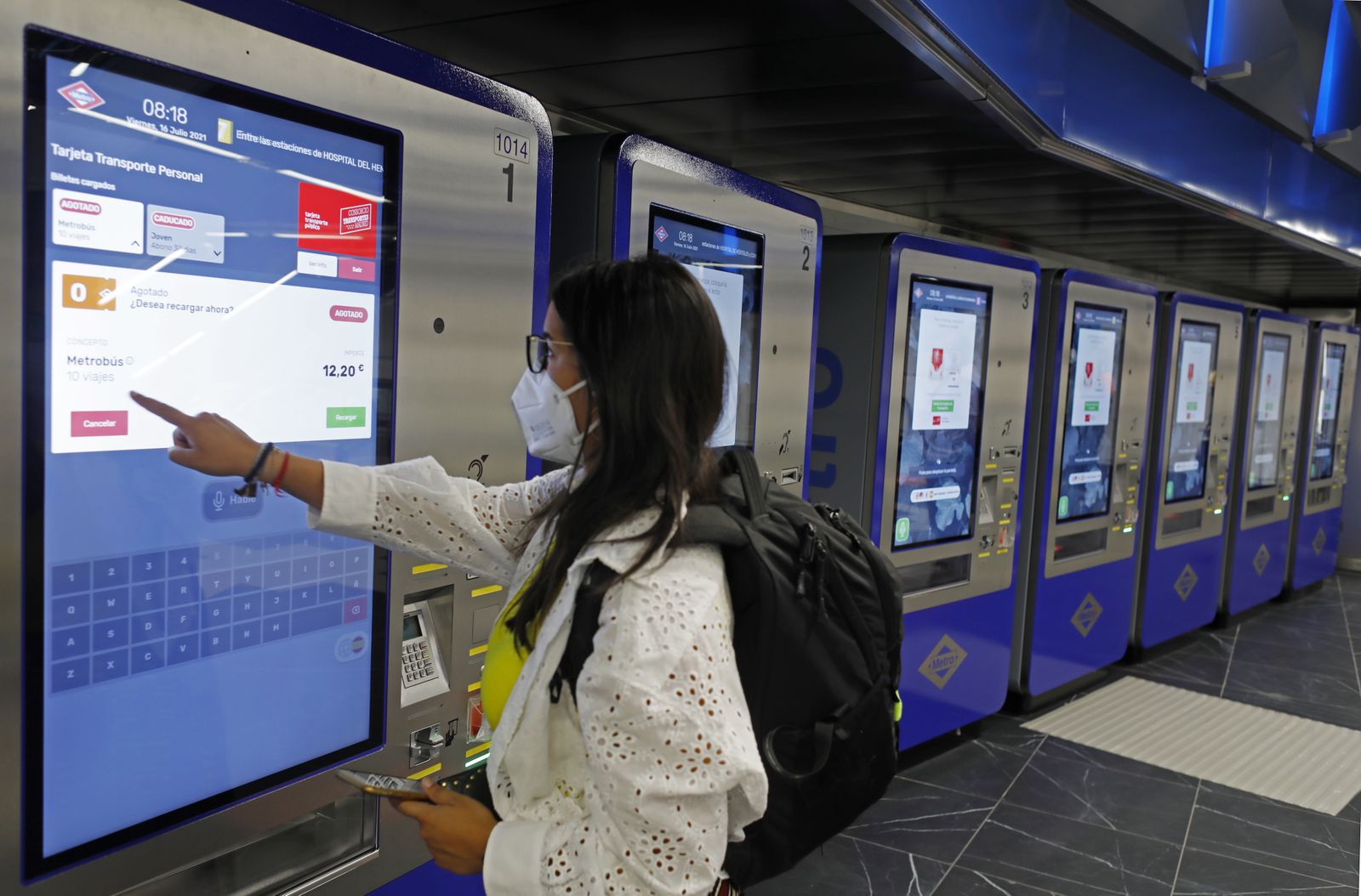 Una mujer compra un abono de 10 viajes en una pantalla táctil en la estación de metro de Gran Vía