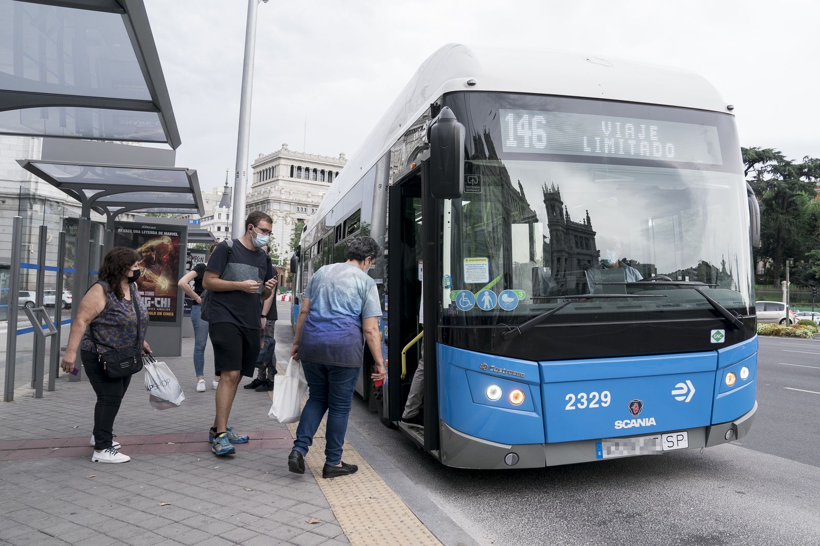 Varias personas suben un autobús de la EMT en la Plaza de Cibeles