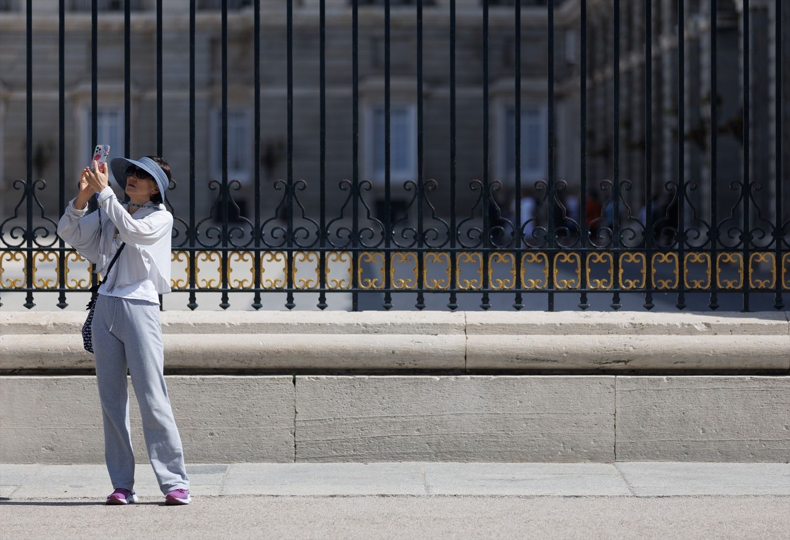 Una turista tomando fotografías frente al Palacio Real de Madrid