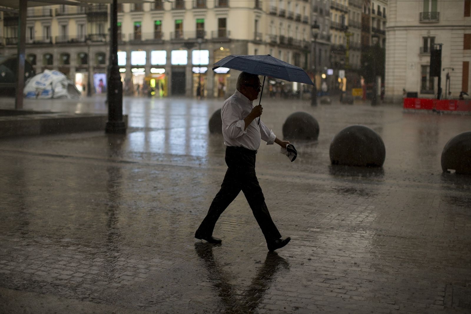 Hombre con paraguas por la calle de Madrid