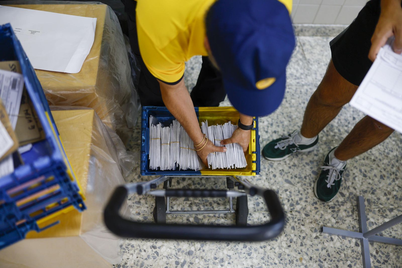 Un trabajador de Correos entrega los sobres con los votos por correo en una mesa