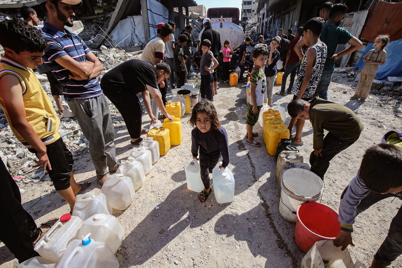 Personas, entre ellos menores, en un punto de abastecimiento de agua en Gaza