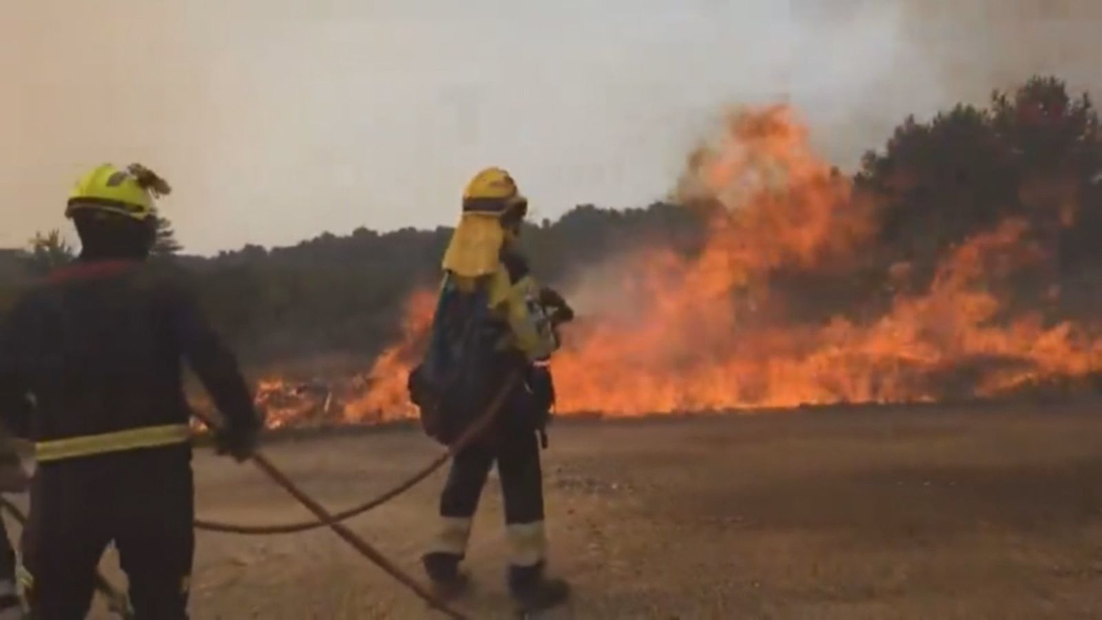 Dos bomberos intentan sofocar un incendio