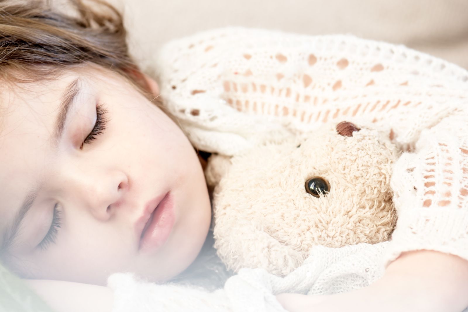 Una niña durmiendo con su osito de peluche