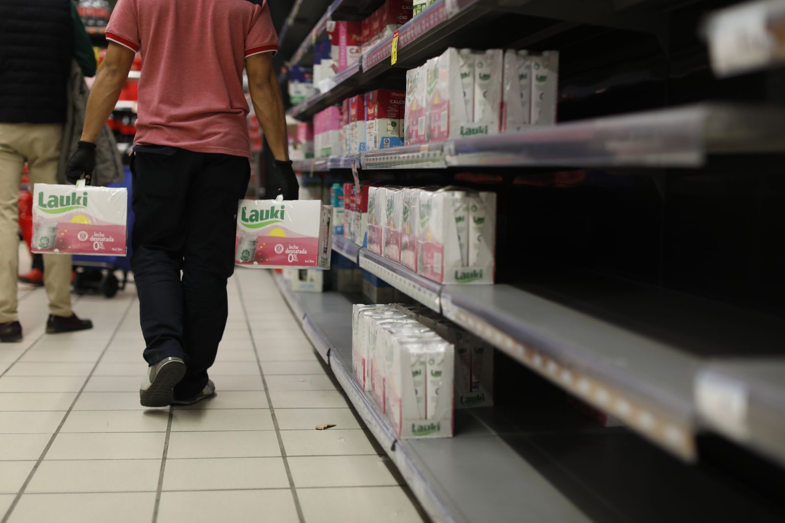 Un reponerdor con dos cajas de leche Lauki, en un supermercado Carrefour