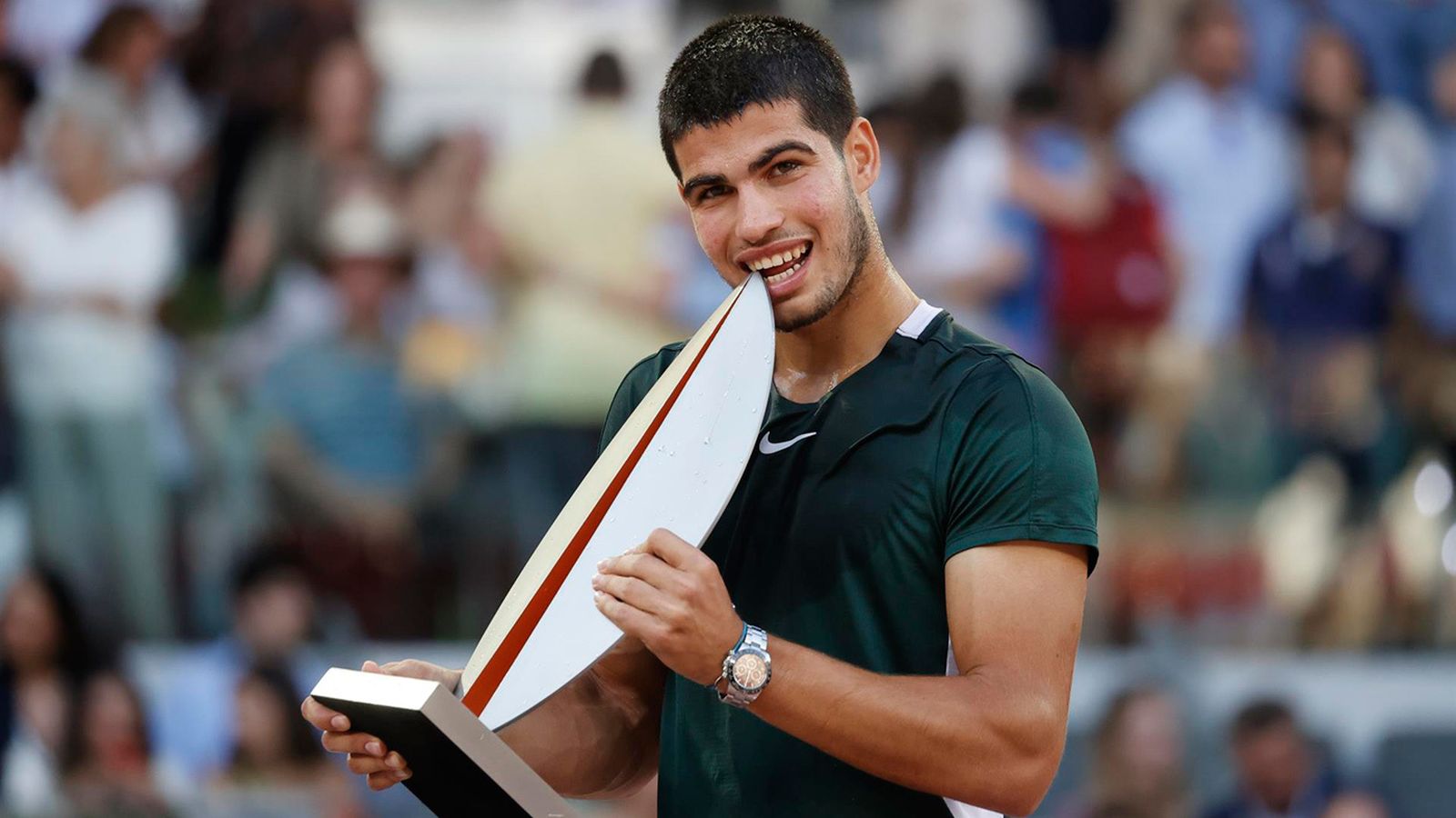El tenista español Carlos Alcaraz muerde el trofeo mientras celebra su victoria en la final de la Mutua Madrid Open tras derrotar al alemán Alexander Zverev