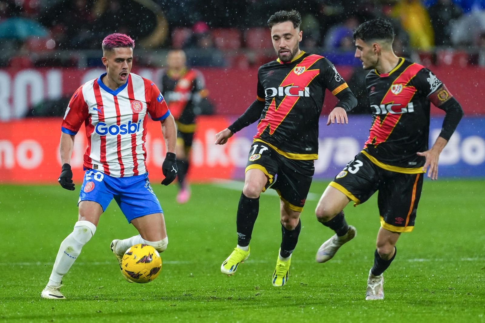 Yan Couto juega un balón ante Unai López y Óscar Valentín en el Girona-Rayo Vallecano de LaLiga