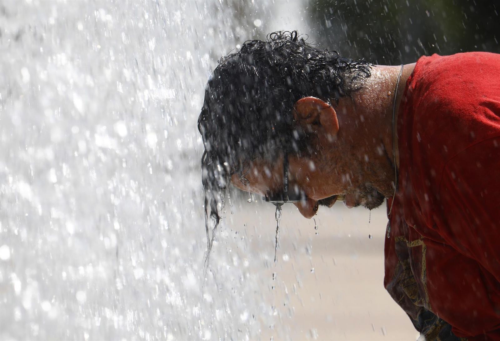 Un hombre se refresca por la ola de calor